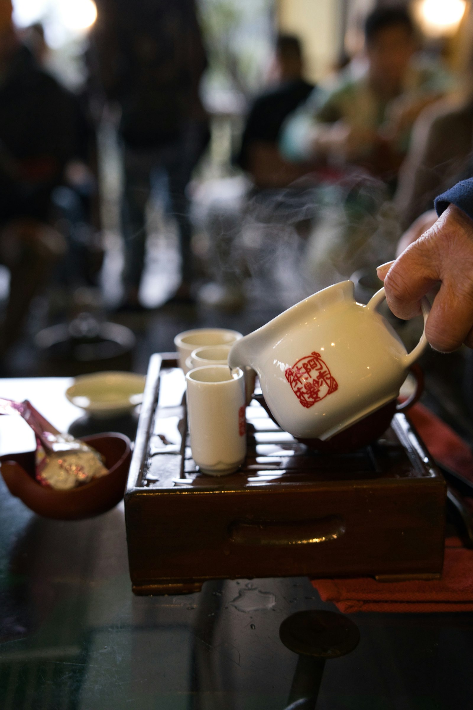 Tea being poured from a ceramic teapot into a small cup
