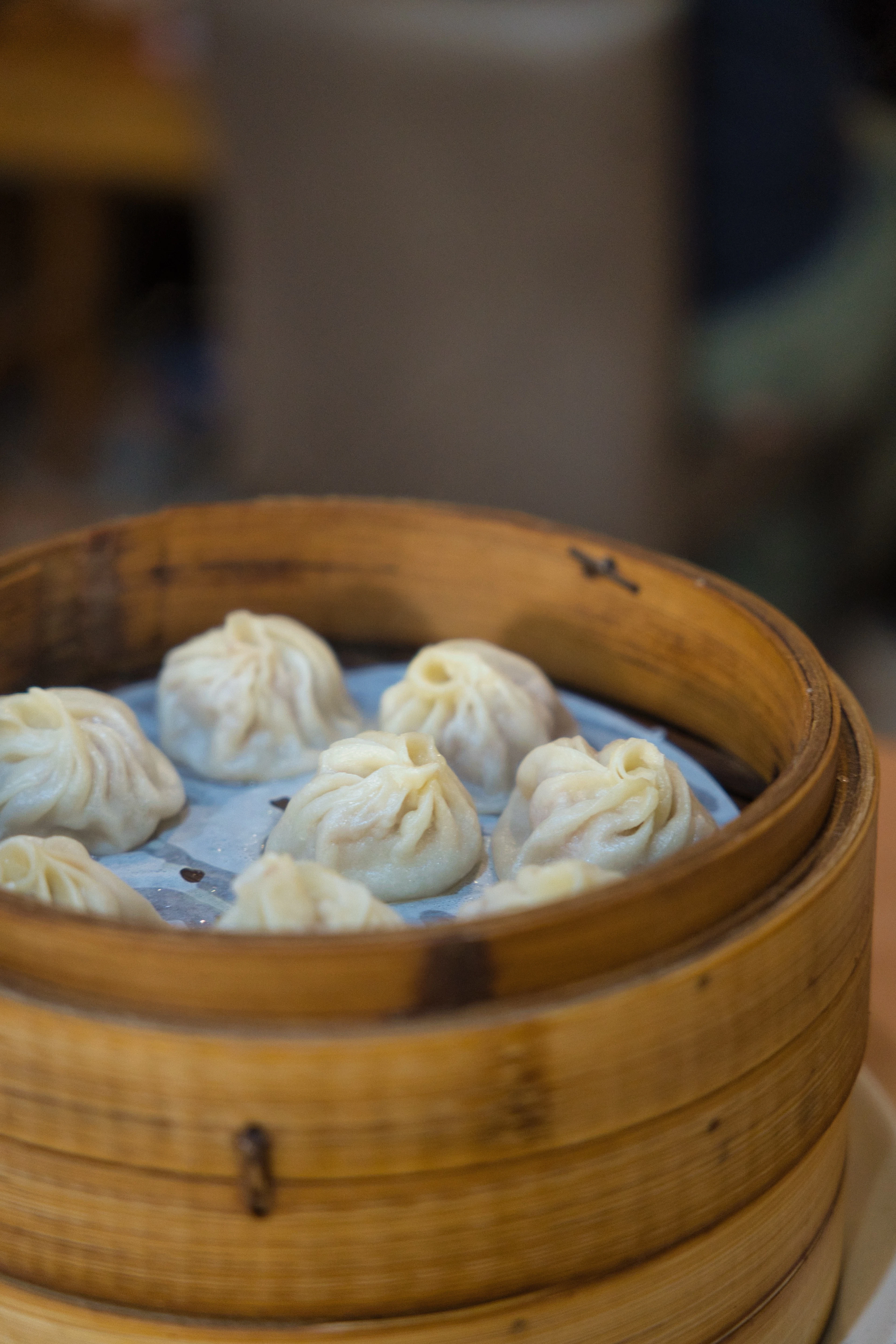 Pleated soup dumplings in a bamboo steamer basket