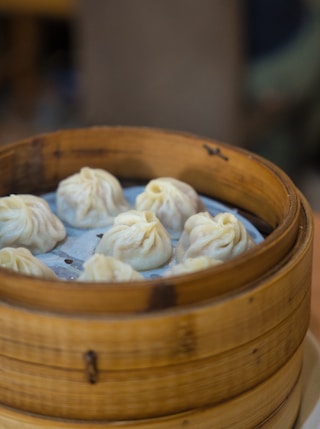 a wooden container filled with dumplings on top of a table