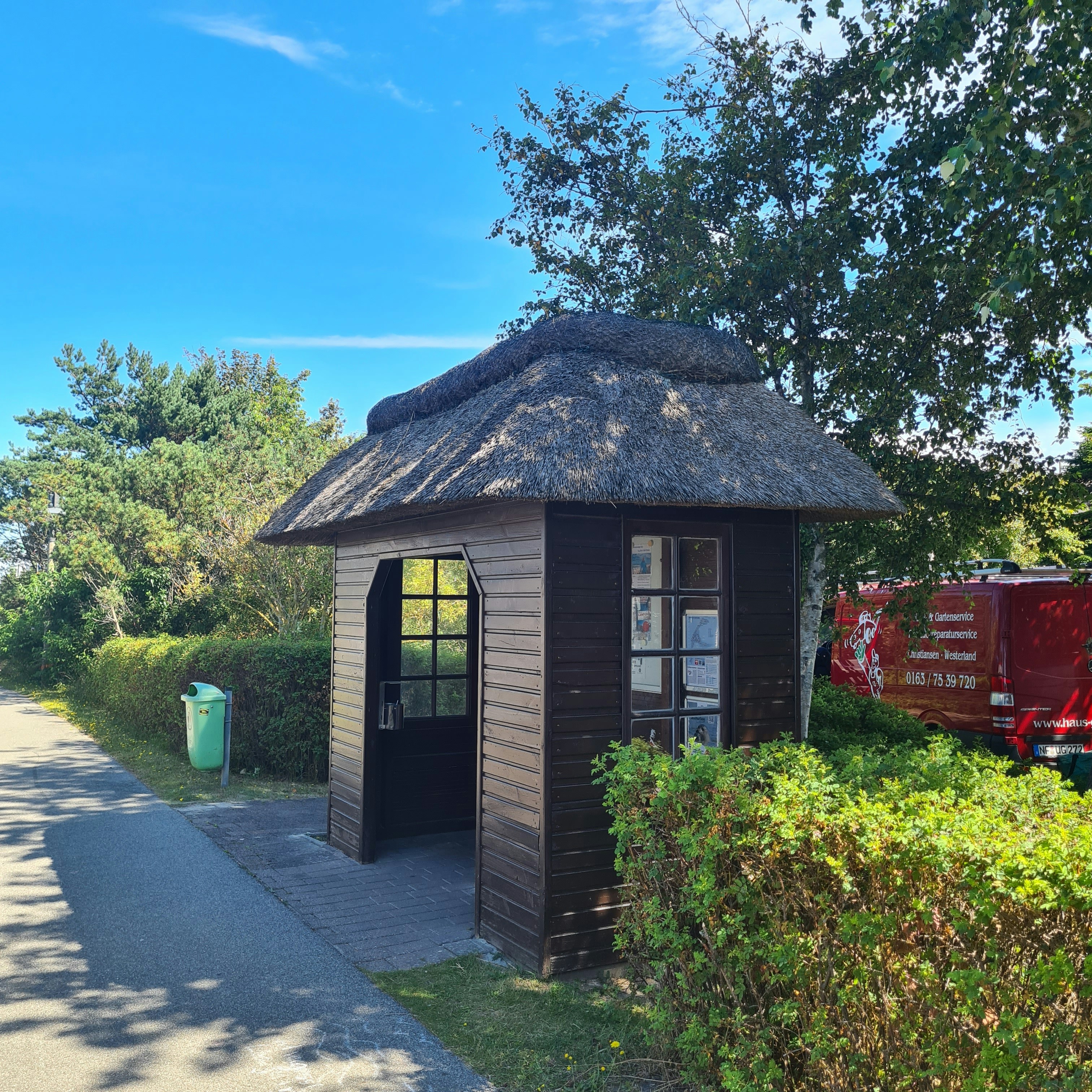 a small building with a thatched roof next to a road