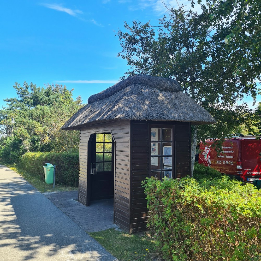 a small building with a thatched roof next to a road