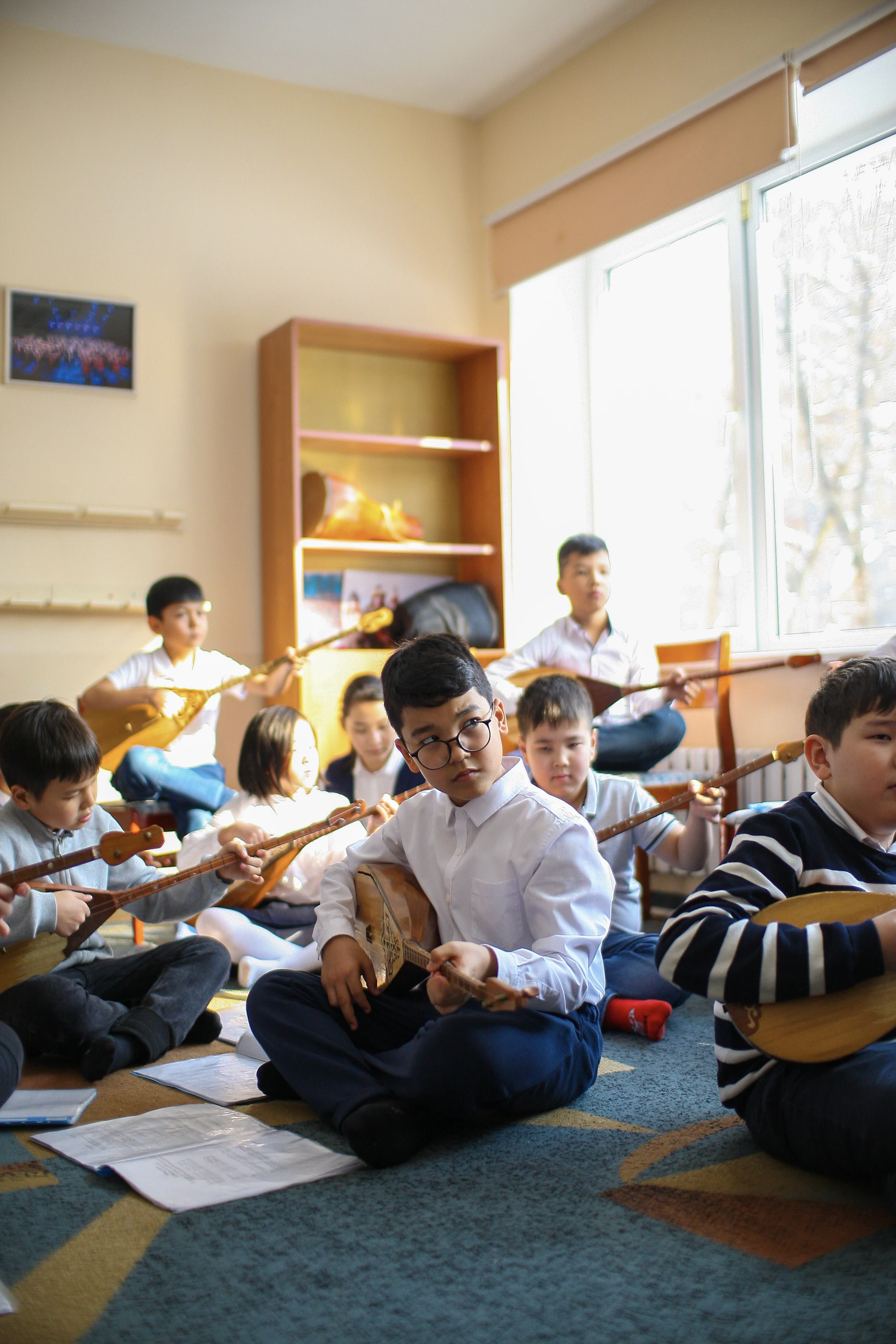 a group of children sitting on the floor playing instruments