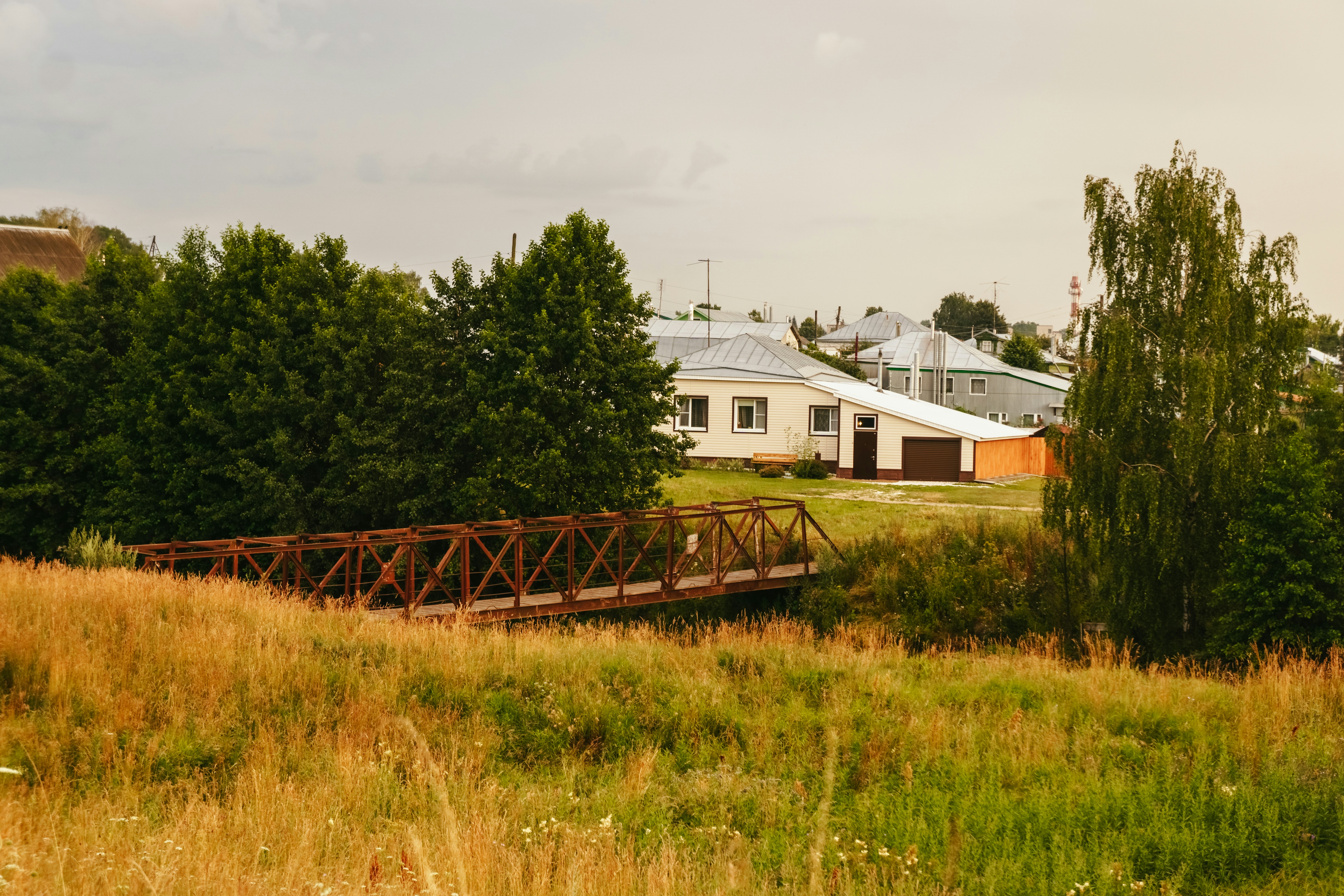 a small bridge over a grassy field next to a house