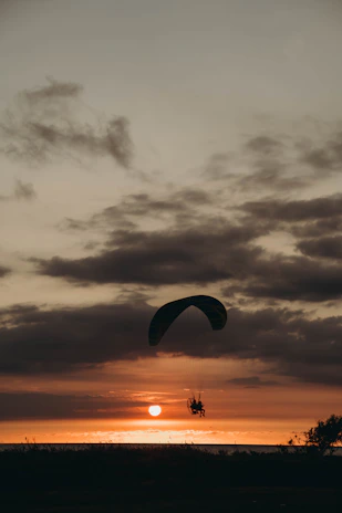 Sunlight filtering through clouds as a paraglider glides peacefully over Ölüdeniz's landscape