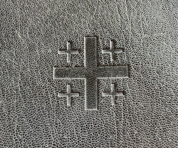 Classic cross emblem embossed on textured old parchment, reflecting heritage and trust.