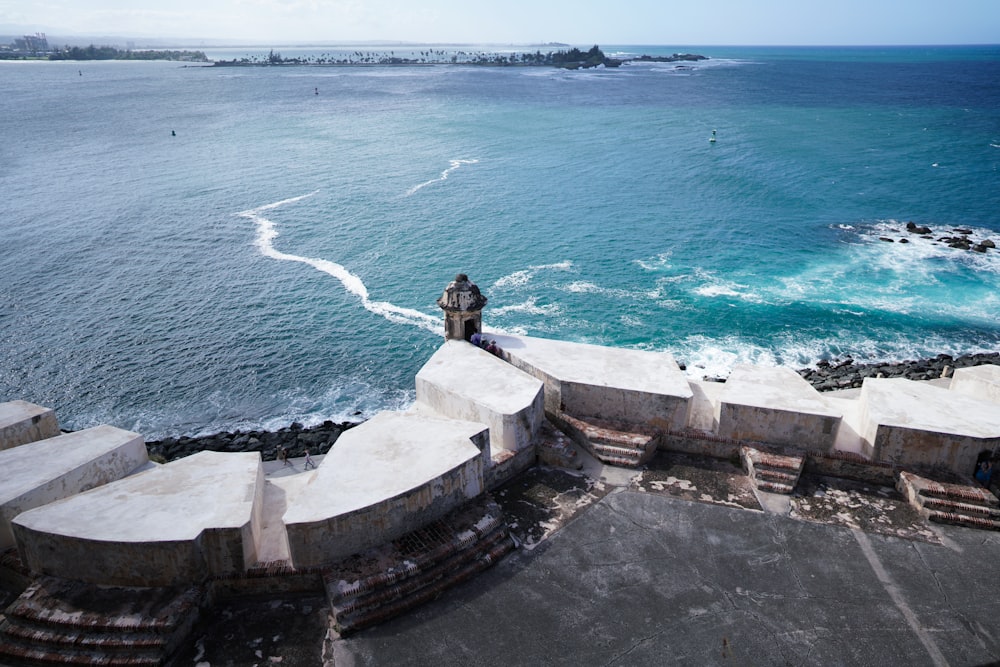 a man standing on top of a stone wall next to the ocean