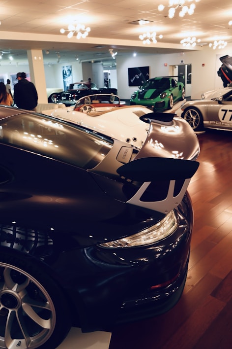 A vibrant showroom with various cars and bikes displayed under bright lights.