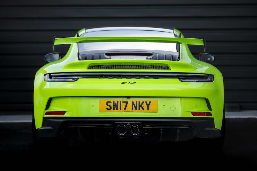 a green sports car parked in front of a garage