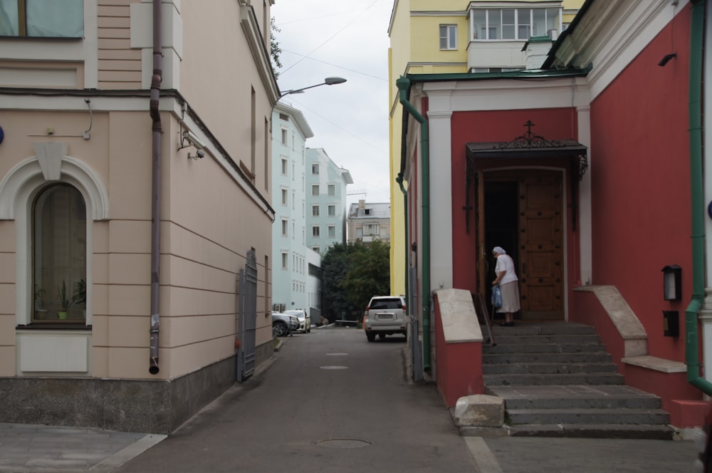 a woman is walking down a narrow street