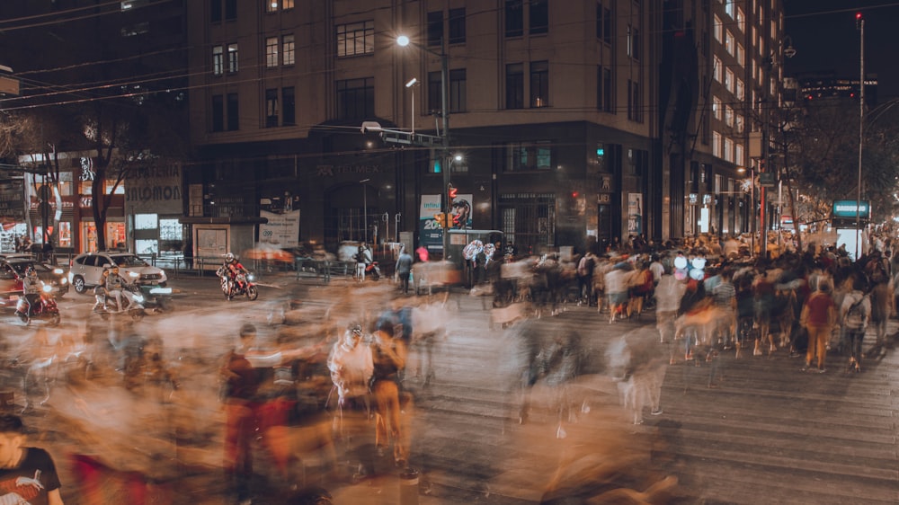 uma multidão de pessoas andando por uma rua à noite