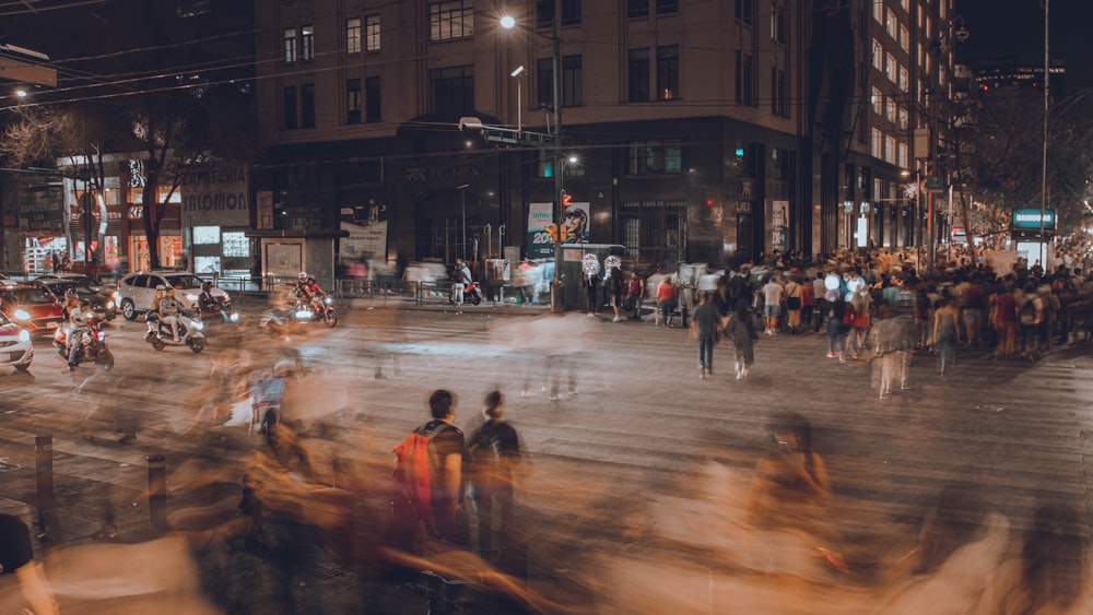 a crowd of people walking across a street at night