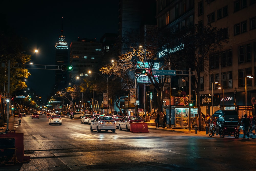 uma rua da cidade à noite com carros dirigindo por ela