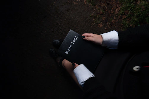 An intense moment from Death Note with Light Yagami holding the notebook under dim lighting.