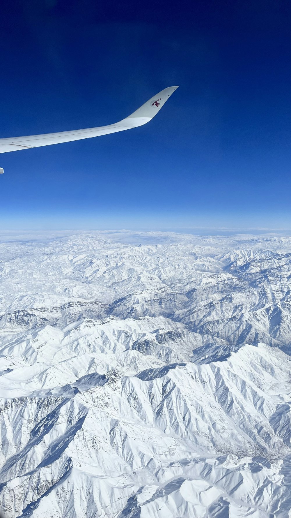 an airplane flying over a snowy mountain range