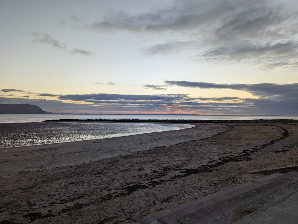 a sandy beach with steps leading to the water