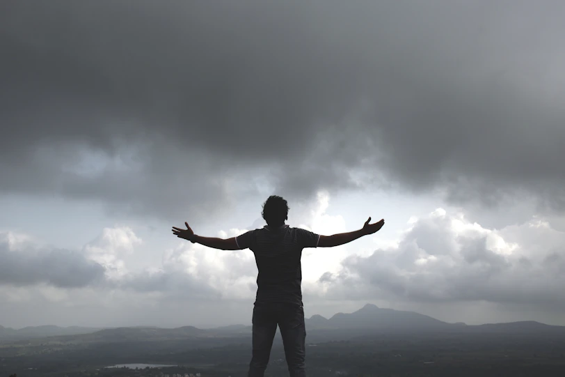 a man standing on top of a hill under a cloudy sky
