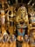 The image displays a collection of ornate Egyptian statues and artifacts featuring vibrant colors and intricate details. Prominent figures include pharaohs and deities adorned in gold, blue, and red.
