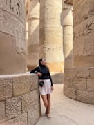 a woman leaning against a wall in front of columns