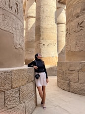 a woman leaning against a wall in front of columns