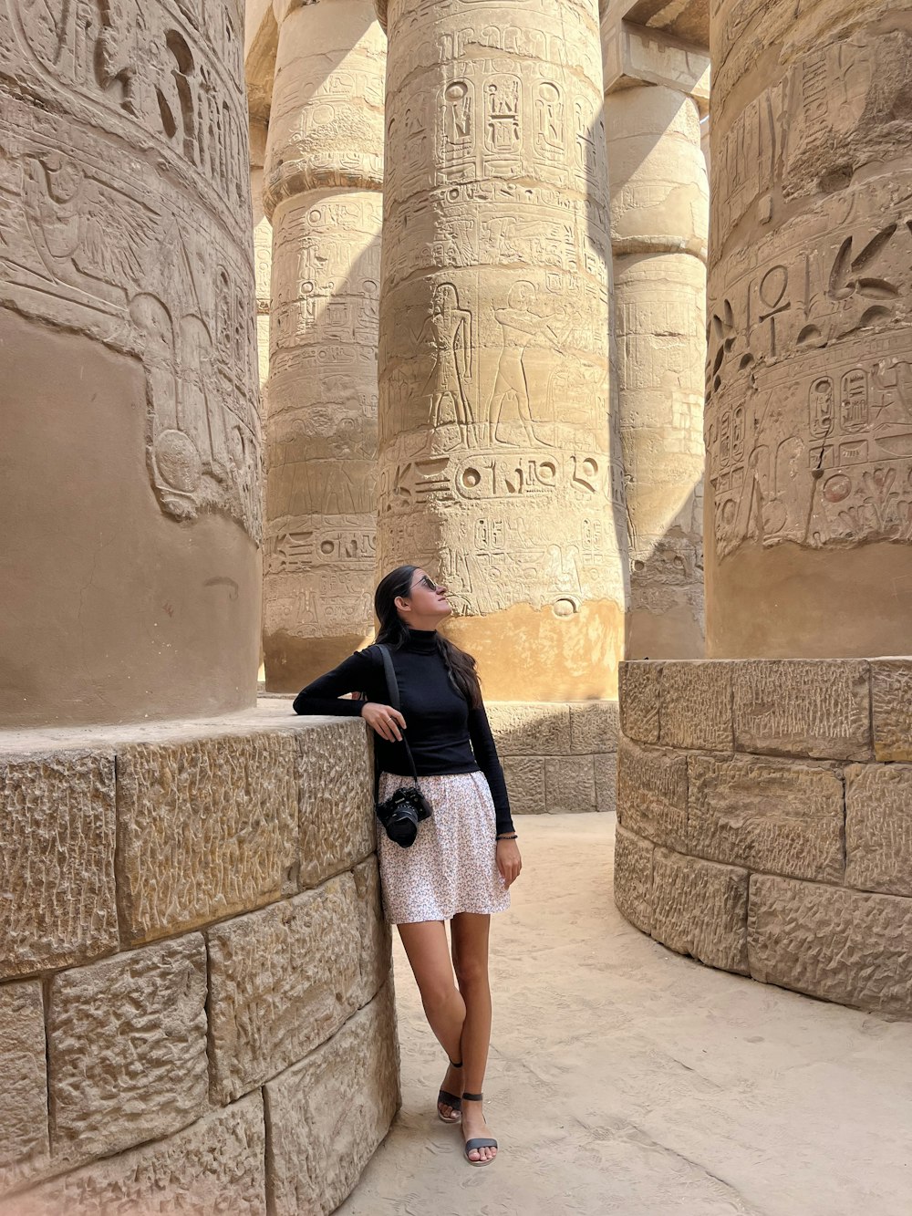 a woman leaning against a wall in front of columns