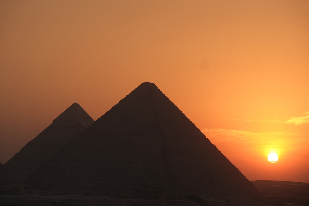 the sun is setting over the pyramids of giza