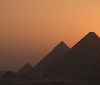 the sun is setting behind the pyramids of giza