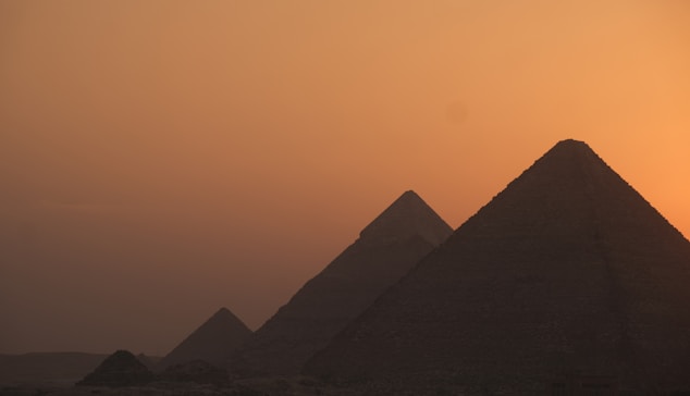 the sun is setting behind the pyramids of giza