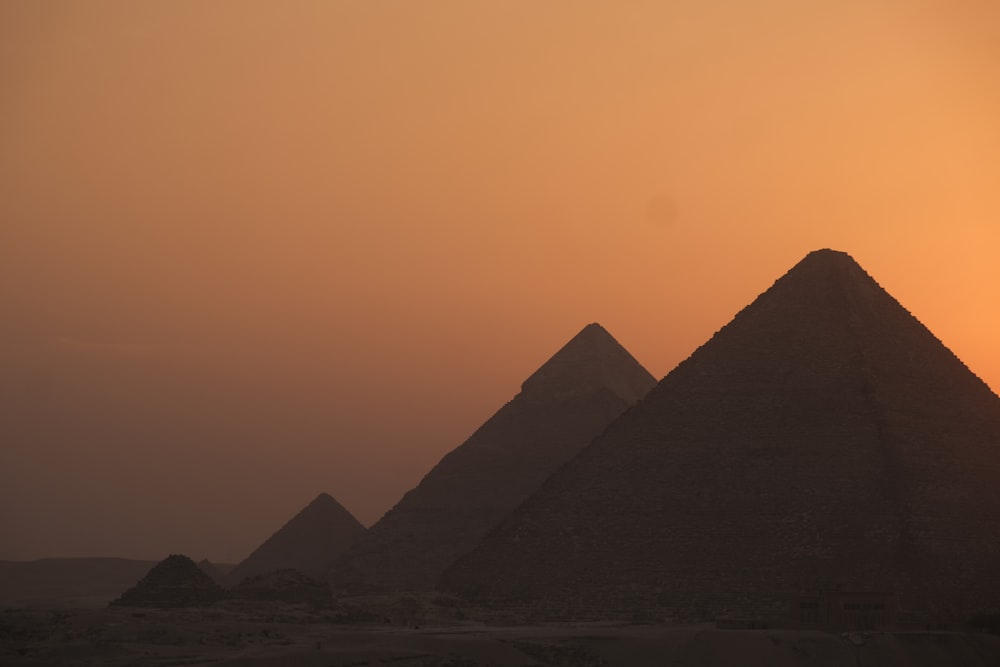 the sun is setting behind the pyramids of giza