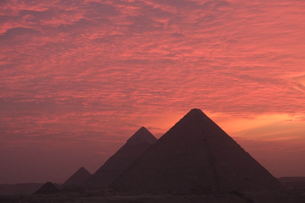 the sun is setting over the pyramids of giza