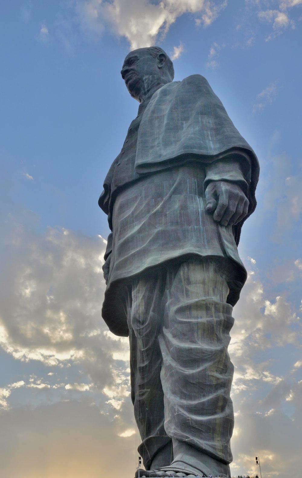 a large statue of a man standing under a cloudy sky