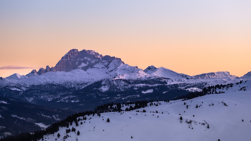 a view of a snowy mountain range at sunset