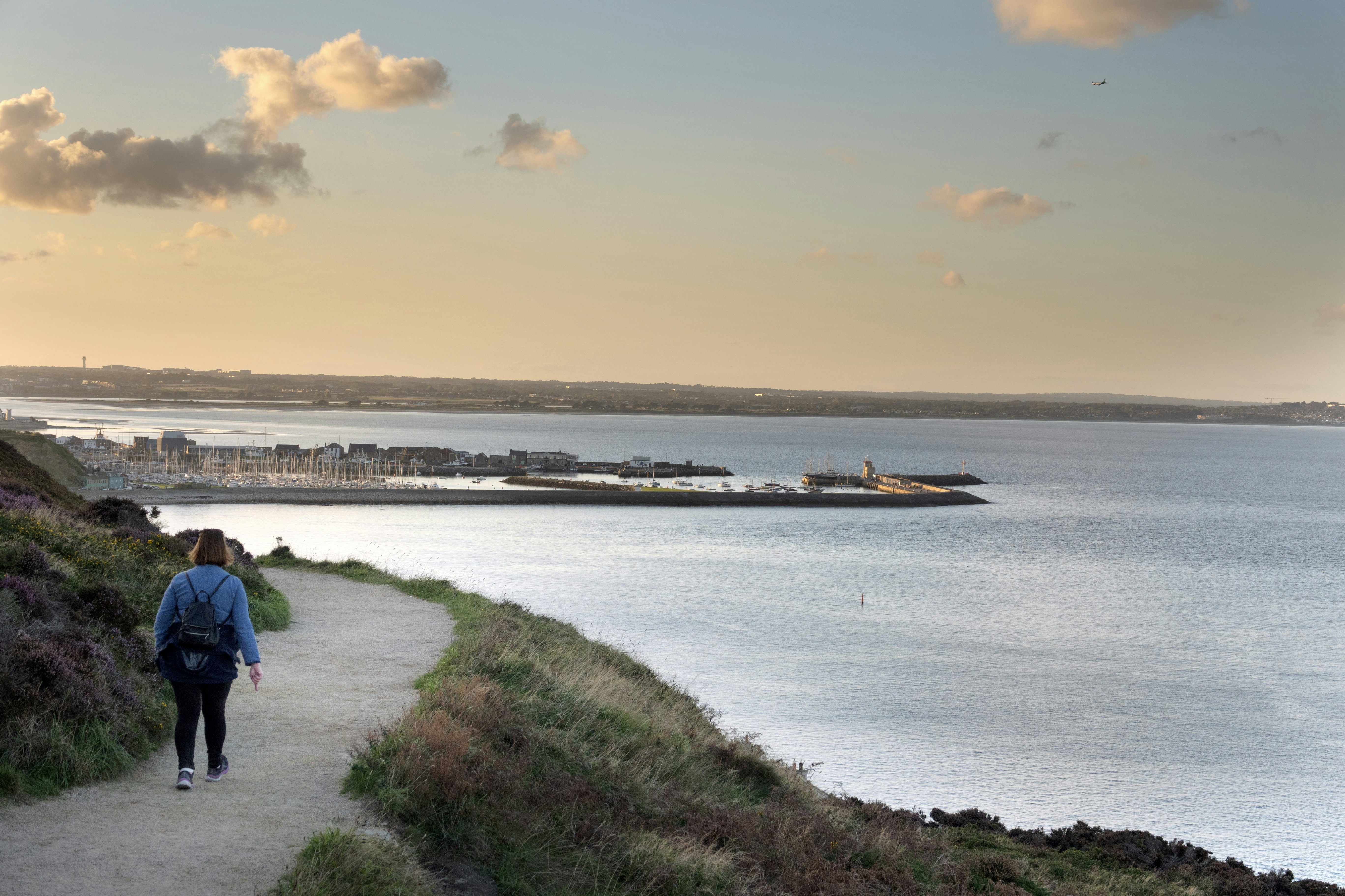 a woman walking down a path next to a body of water