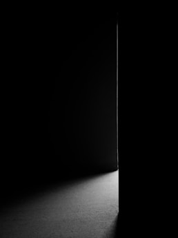 A softly lit doorway with a narrow beam of green light shining through the crack.