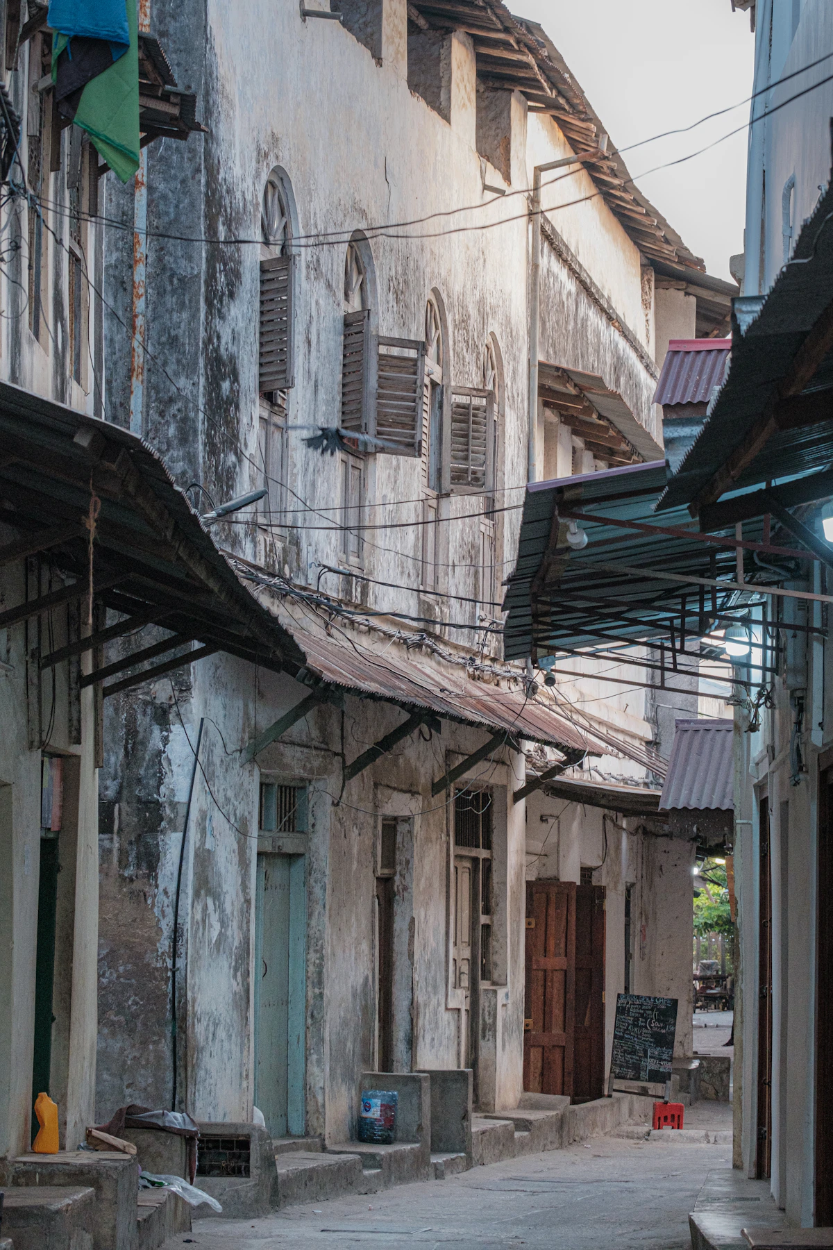 A narrow historic lane between weathered coral-stone buildings in Stone Town