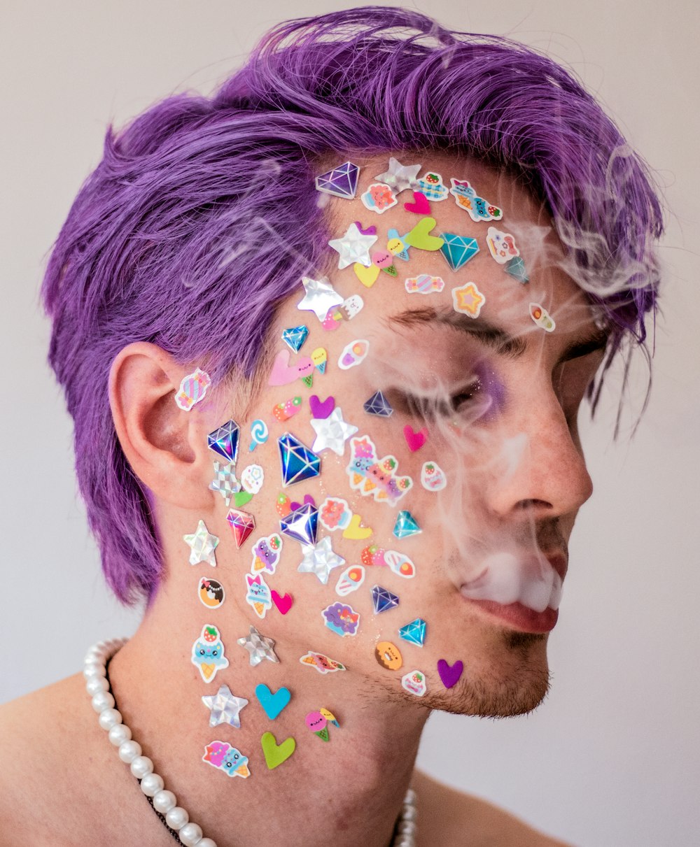 a man with purple hair and lots of stickers on his face