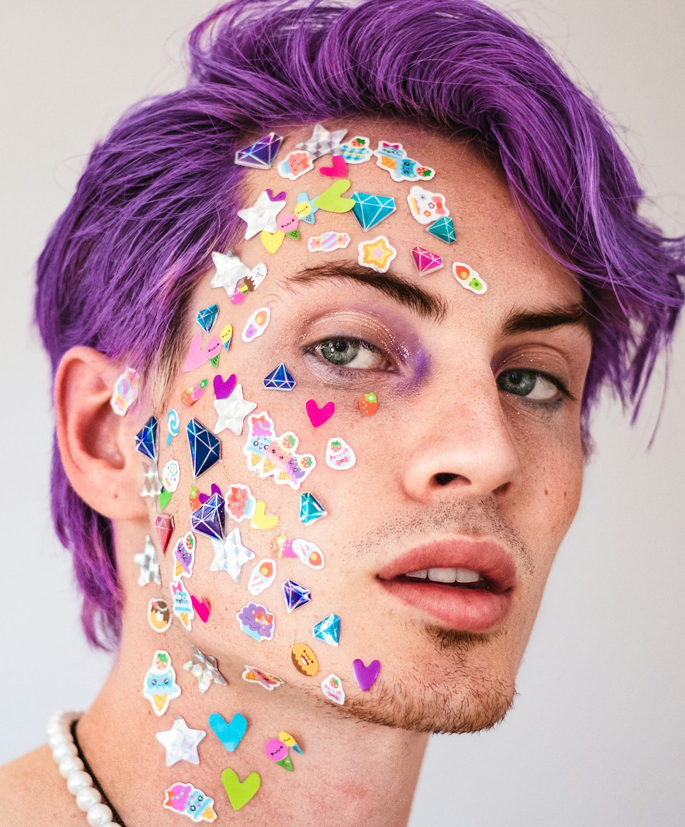 a man with purple hair and lots of stickers on his face