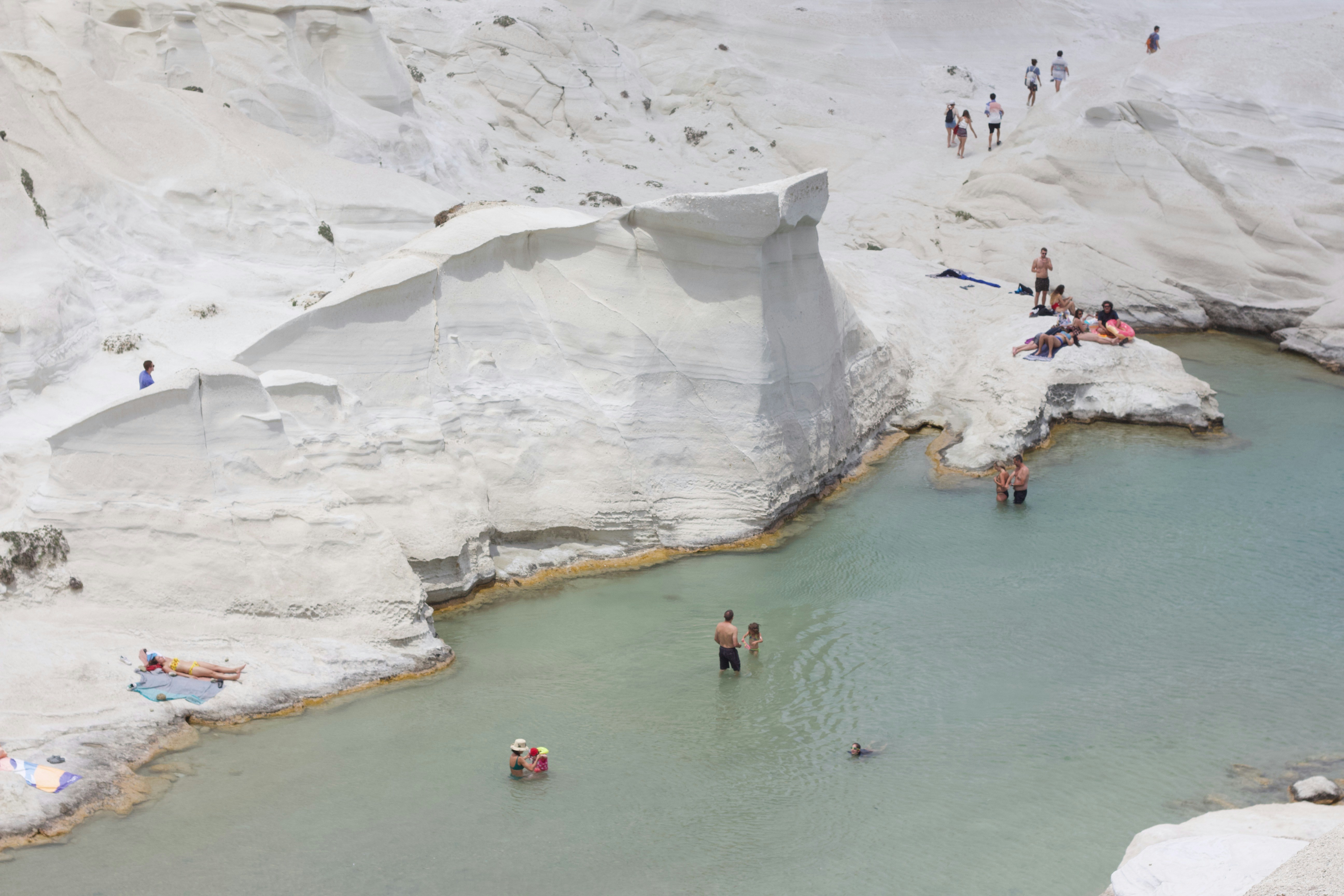 a group of people standing around a pool of water, 
