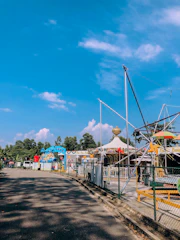 A family enjoying a sunny day at a colorful amusement park with balloons.