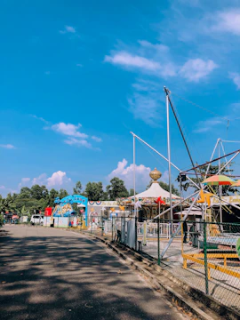 A family enjoying a sunny day at a colorful amusement park with balloons.