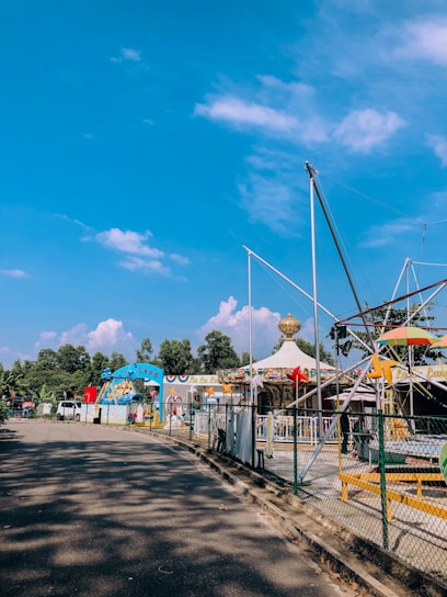Children enjoying colorful rides at a sunny outdoor festival in a green park.