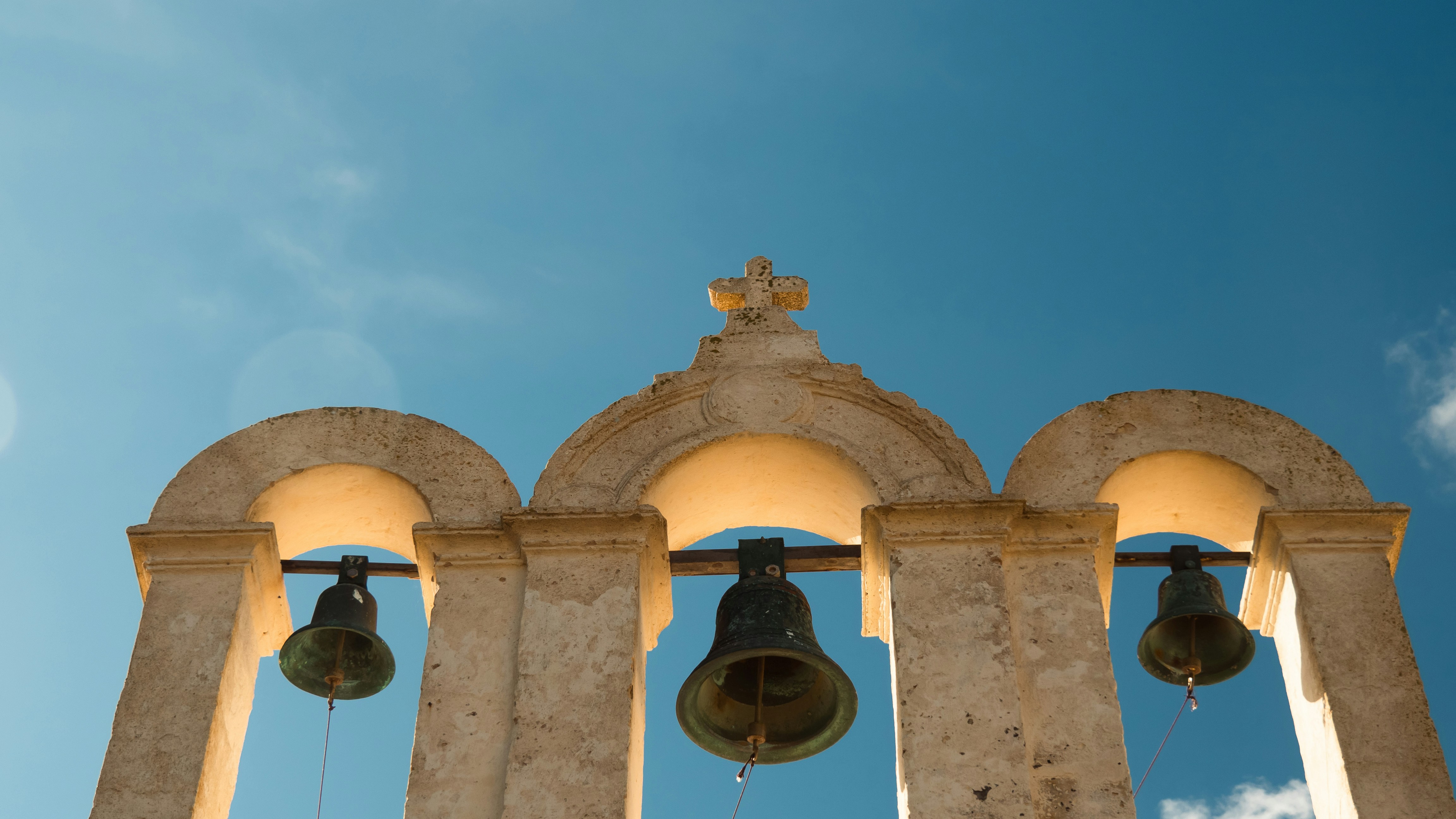 A group of bells hanging from the side of a building photo Free