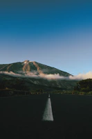 a long straight road with a mountain in the background