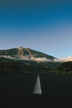 a long straight road with a mountain in the background