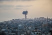 smoke billows from a factory in a city
