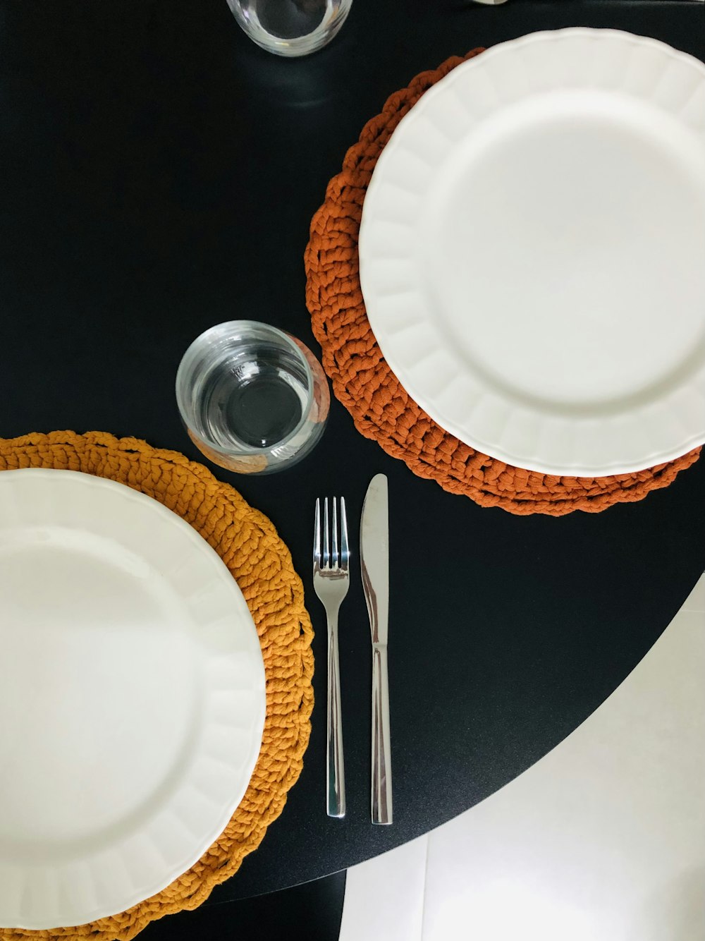 a black table topped with white plates and silverware