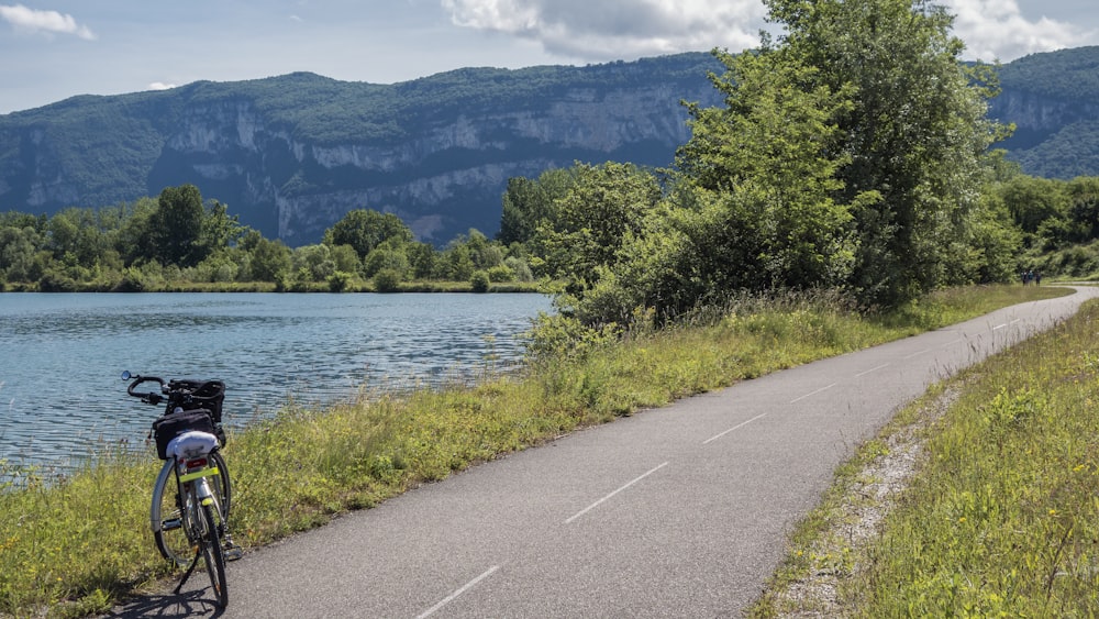 a bicycle parked on the side of a road next to a lake