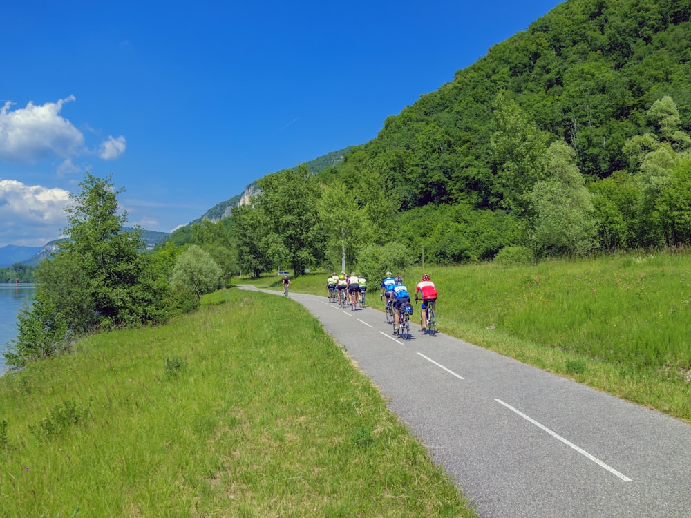 a group of people riding bikes down a road next to a lake