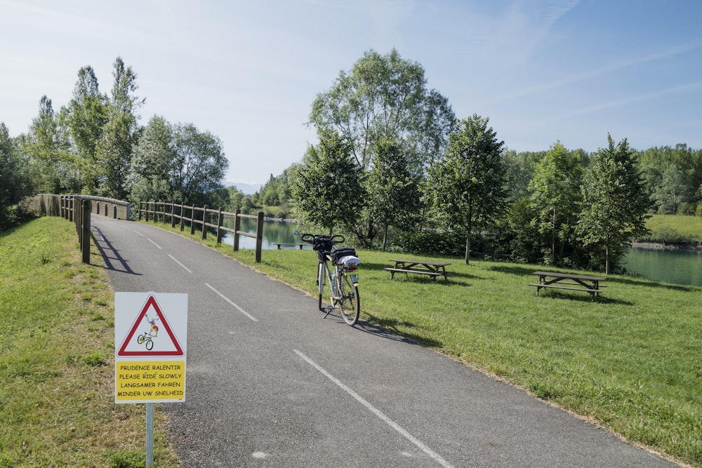 a bike parked on the side of a road next to a park