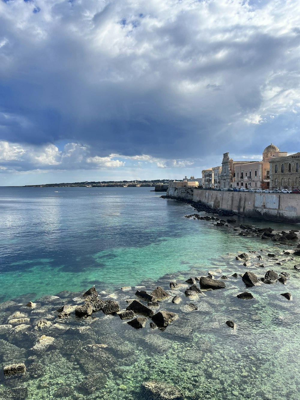 a body of water next to a stone wall