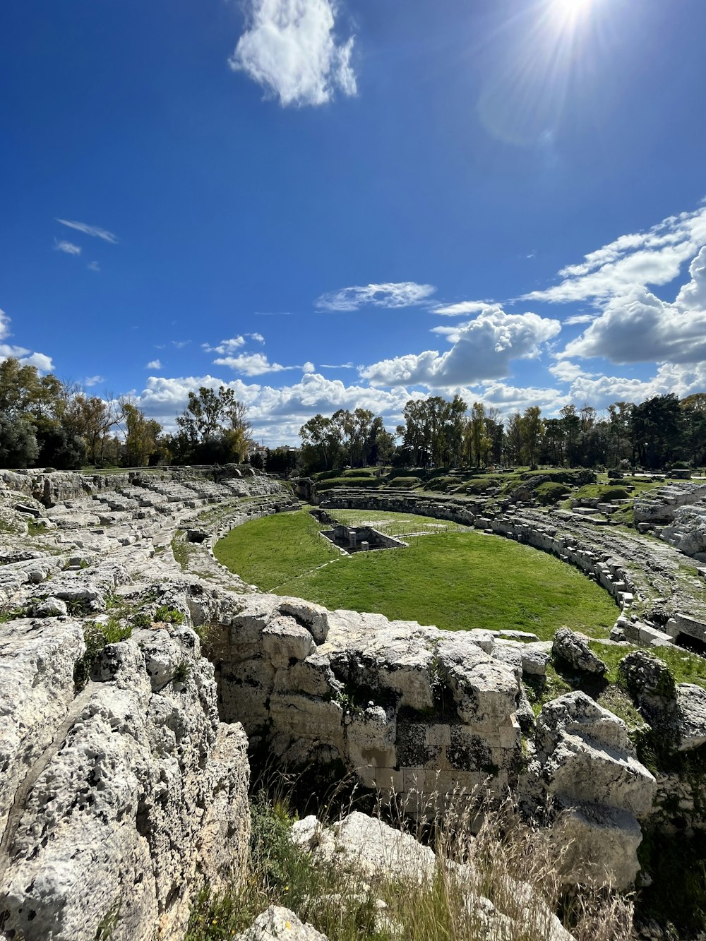 Ein grasbewachsenes Feld, umgeben von Felsen unter blauem Himmel